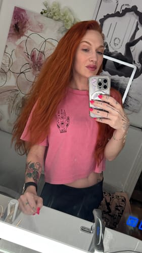Reviewer in a mirror selfie wearing the pink, cropped Bitchcraft T-Shirt.