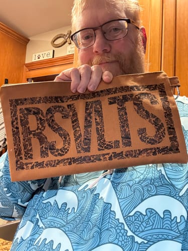 Reviewer holding up the brown Heavy Weight Utility Pouch, showing the black RSVLTS logo.