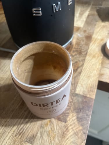 Customer shows an empty container of DIRTEA Coffee on a kitchen counter, ready for their next delivery.