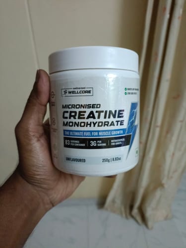 Customer's hand holding a white tub of Wellcore Micronised Creatine Monohydrate.