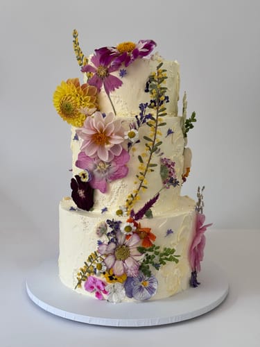 Reviewer's three-tiered white cake decorated with an assortment of colorful pressed flowers.