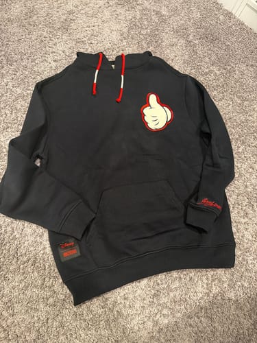 Customer's black Disney "You Got This, Pal!" hoodie laid flat, showing the Mickey Mouse thumbs-up patch and red accent drawstrings.