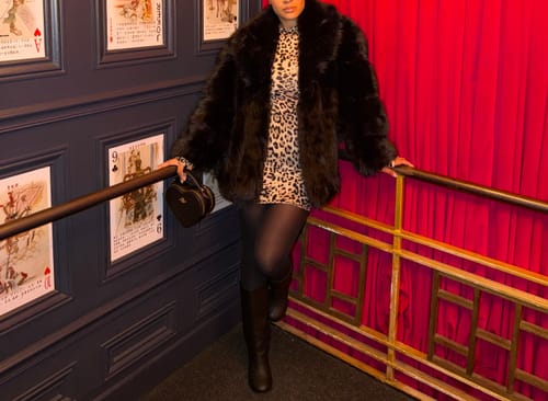 Reviewer wearing the plush, black Faux Mink Pelted Coat over a leopard-print dress.