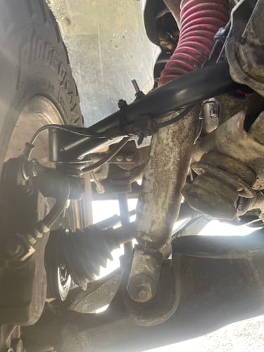 Reviewer's view of the old, stock upper control arm on a truck before replacement with the new product.