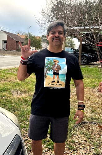 Reviewer smiling outdoors while wearing the black El Halftime OG T-Shirt and making a hand gesture.