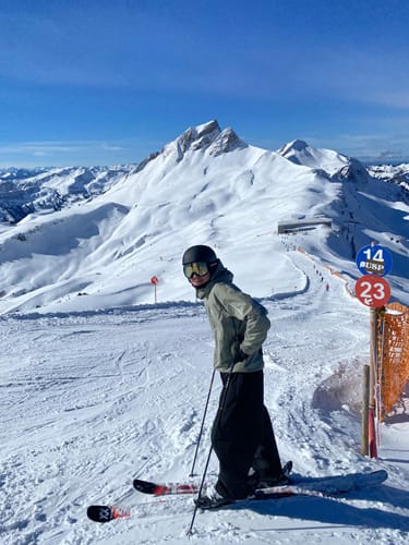 Reviewer wearing the baggy black Durable Snow Pants while skiing on a sunny mountain slope.