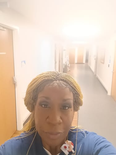 Reviewer in a hallway wearing the blonde Annelis Micro twist Wig, showing the natural-looking lace front.