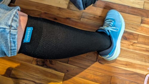 Customer wearing a black Performance Eucalyptus Compression Sock on their leg with a blue sneaker.