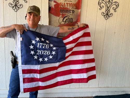 Customer holding the 1776 to 2026 Betsy Ross Flag open on a porch, showing the embroidered design.
