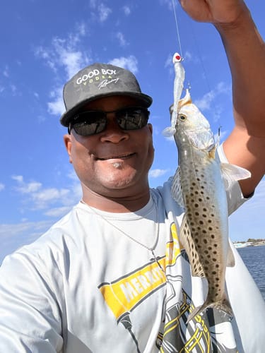 Customer holding a speckled trout caught on a sunny day with the white Knockin Tail Lure.