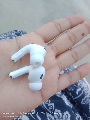 A reviewer holding a pair of white LOT Earbuds in their open palm.