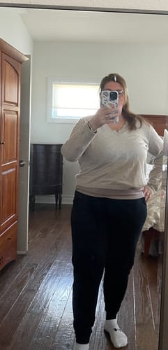 Reviewer taking a mirror selfie in a bedroom, showing the fit of the black Willa Joggers.