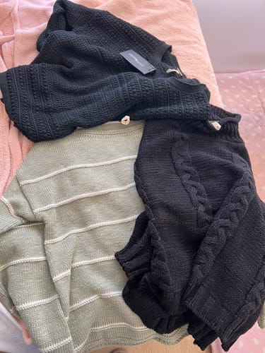 Una clienta muestra el chaleco Astana verde/crudo que compró, junto con otros dos jerséis oscuros.