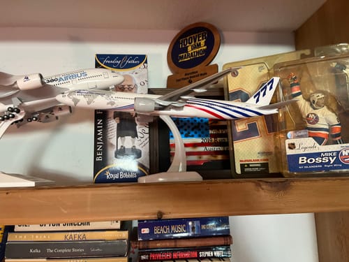 Customer's Hogan Boeing 777-300ER model plane assembled on its stand, displayed on a shelf with other collectibles.