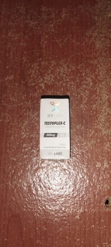 Un cliente muestra la caja de Testoplex-C 300mg sobre una superficie de madera.