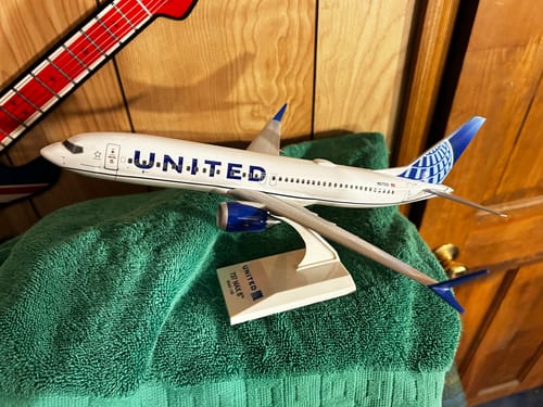 Customer's SKYMARKS UNITED 737MAX8 model plane on its display stand, resting on a green towel.