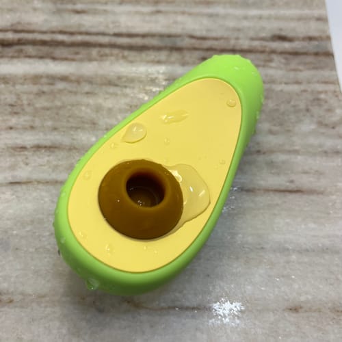 Customer's Avo Clitoral Massager covered in water droplets on a wet marble surface, showing its waterproof quality.