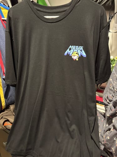 Reviewer's black Mega Man crewneck tee showing the small front logo with a Met character.