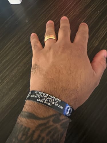 Customer wearing their customized black bracelet with white memorial text on their wrist.
