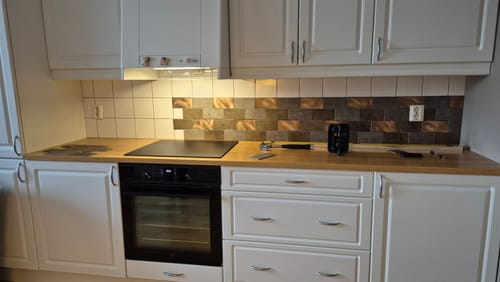 Kundens Bente selvklebende veggfliser installert som en moderne kjøkkenplate bak en stekeovn.