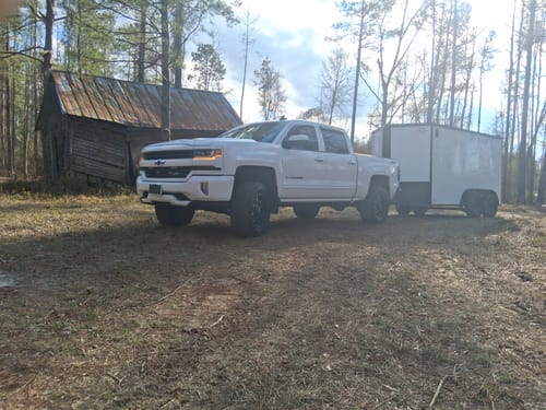 Customer's lifted white Silverado 1500 towing a trailer after installing the control arm and sway bar.