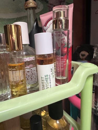 Customer's amber-colored Sweet Wishes perfume on a light green shelf among other beauty products.
