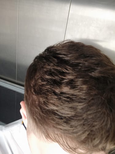 Gros plan sur la chevelure dense et brune d'un client, montrant le résultat du Pack d'Odin.