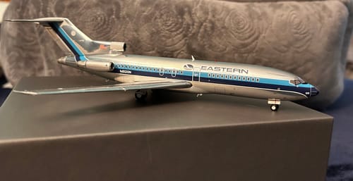 A reviewer's detailed GEMINI200 EASTERN 727-100 model plane with a silver and blue livery, shown on a box.