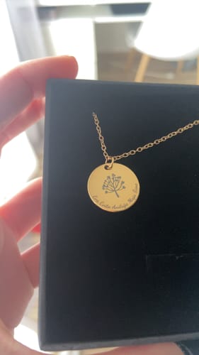 Customer holding the black presentation box open to show the engraved gold Družinsko Drevo necklace.