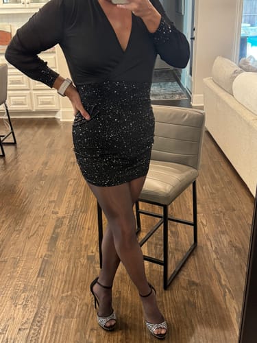 Reviewer standing in a black dress, wearing sheer, glossy seamless tights and heels.