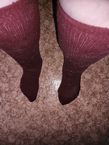 Recensent som visar passformen på ett par mörkröda Diasocks Komfortstrumpor.