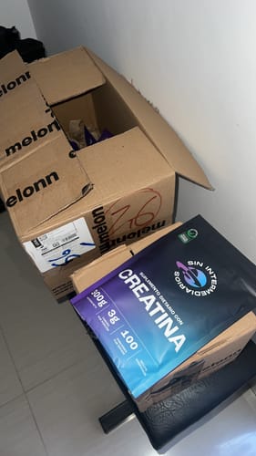 Reseñador muestra el empaque de Creatina Monohidrato junto a la caja de envío abierta.