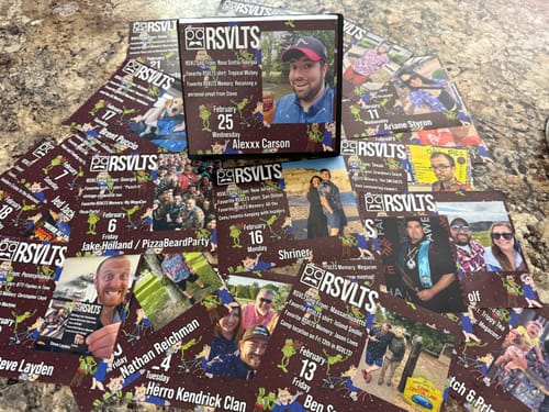 Reviewer's RSVLTS 2026 Calendar displayed with its individual daily photo pages fanned out across a countertop.