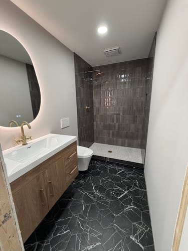 Customer's Belgian Floating Vanity installed in a modern bathroom with dark hexagonal floor tiles and a shower.