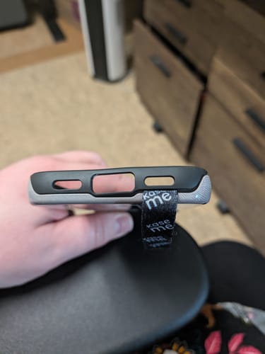 Close-up of the customer's black Phone Loop installed, showing it separating the two layers of the phone case at the bottom.