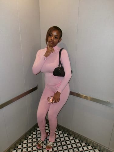 Customer wearing the pink Seamless Logo Turtleneck, showing the form-fitting outfit in an elevator.