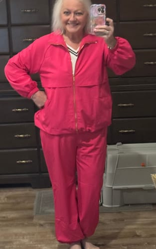 Customer trying on the bright pink Two Piece Zip Up Jacket & Jogger Set indoors.