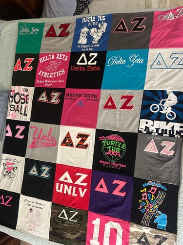 Customer's colorful Premium T Shirt Quilt made from sorority t-shirts, spread out on a bed.