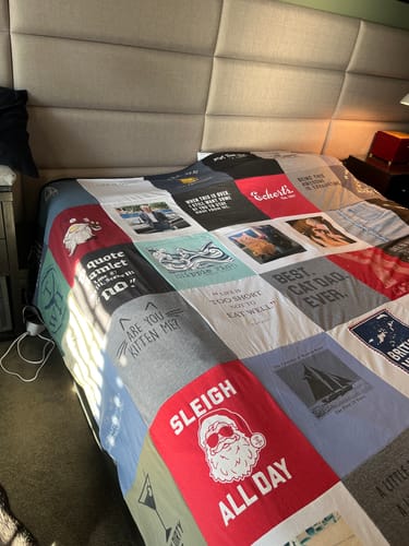 Customer's custom Premium T Shirt Quilt with many colorful t-shirt panels spread across a bed.