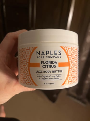 Customer's hand holding the white jar of Florida Citrus Luxe Body Butter.