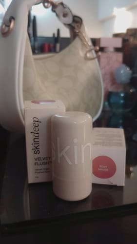 Reviewer's VELVET FLUSH Lip+Cheek Blush stick and packaging for the Rosy Mauve shade on a table.