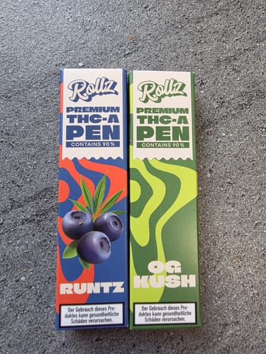 Customer's two boxes of ROLLZ THCA Vapes, the Runtz and OG Kush strains, standing side-by-side on a stone surface.