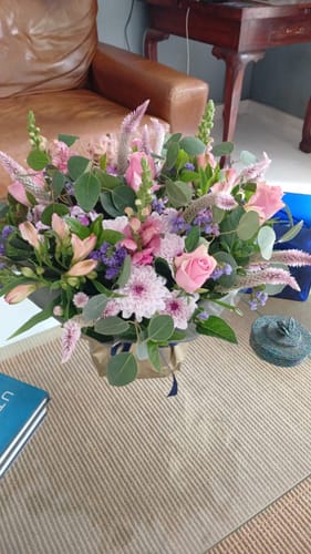 Customer's beautiful Harmony Flower Arrangement with pink and purple flowers sitting on a glass table.