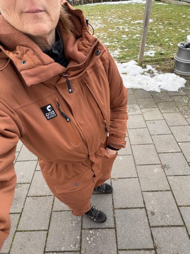 Anmelder, der har en karamelfarvet Jumpsuit 2.0 på, fotograferer sig selv fra oven udendørs.