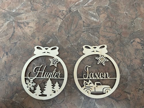 Customer's two personalized wooden Christmas ornaments. One for 'Hunter' with a tree design, one for 'Jaxon' with a truck design.