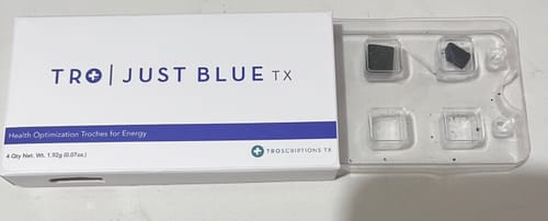 Reviewer shows the Just Blue packaging, with the clear tray partially slid out revealing two dark troches.