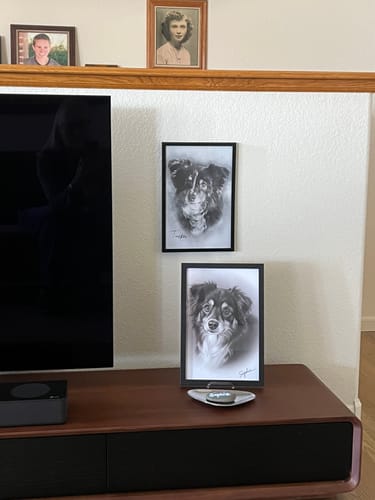 Customer's two Personalized Pet Drawing Style Portrait Prints of a dog, one hanging on the wall and one on a media console.