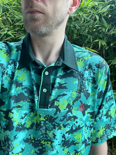Customer wearing the Predator polo, showing the vibrant green and black jungle camouflage pattern with character details.