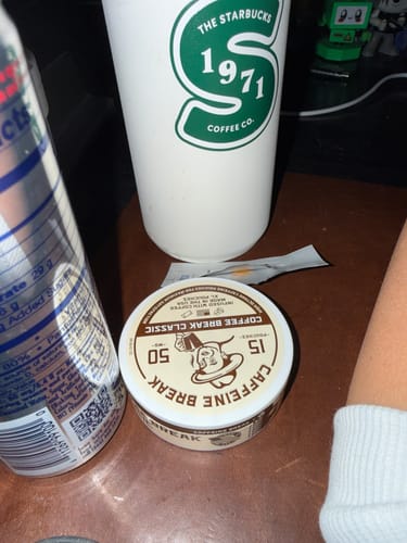 Reviewer's tin of Coffee Break Caffeine Pouches on a desk next to a coffee cup and a can.