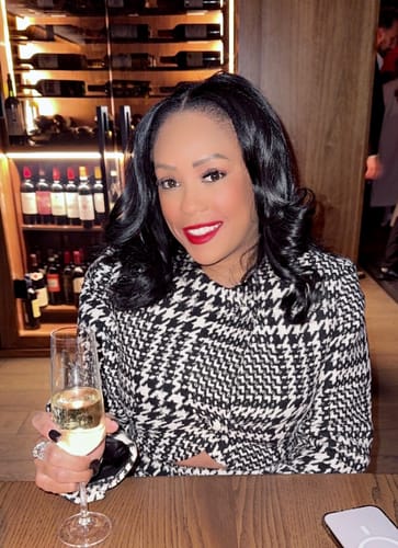 Customer showing the tailored fit of the Houndstooth Plaid Cropped Blazer while seated at a table.